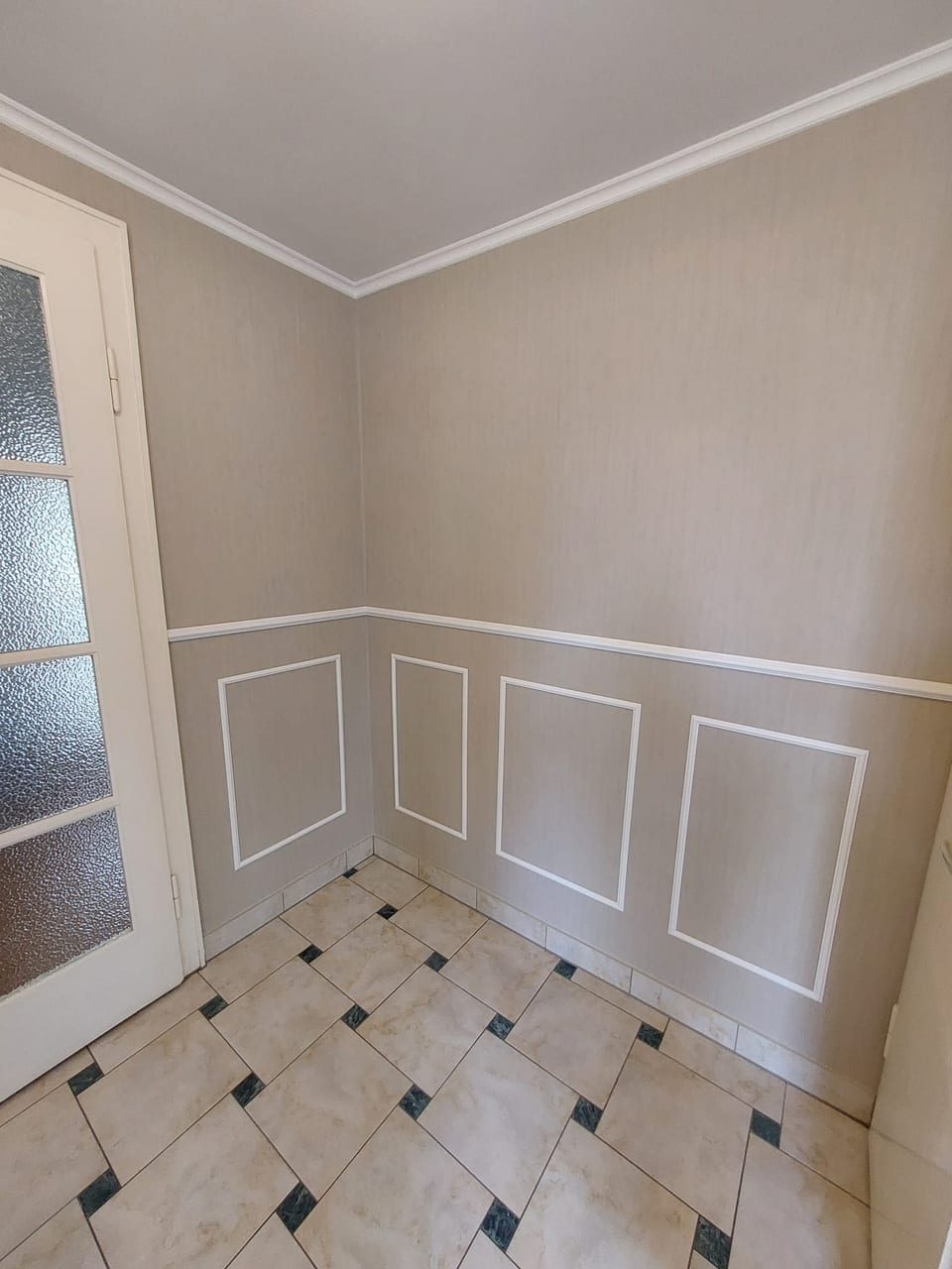 Elegant gestaltete Wand mit weißen Stuckprofilen und hellem Naturton